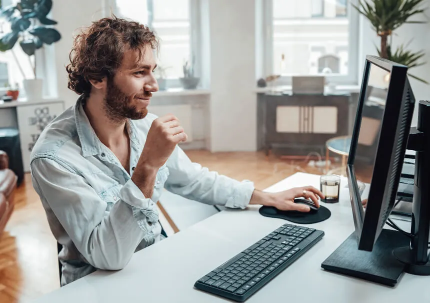 A website visitor interacting with a high-converting website pop-up offer on a desktop computer. A smiling man in a light shirt browsing an online store with an optimized lead capture form.
