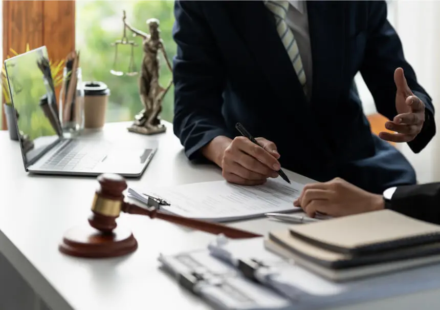 Legal consultation analyzing GDPR compliance in marketing automation – a professional and a client reviewing privacy data documents at a desk with a laptop, Lady Justice statue, and a judge's gavel.