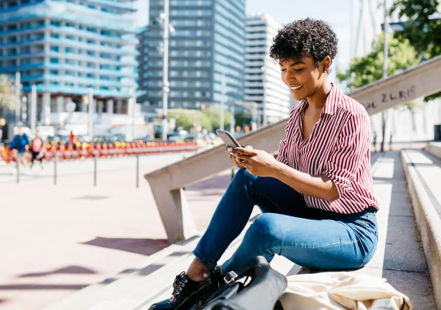 A happy customer reading a promotional e-commerce SMS on her smartphone that drives sales and boosts online store conversions.