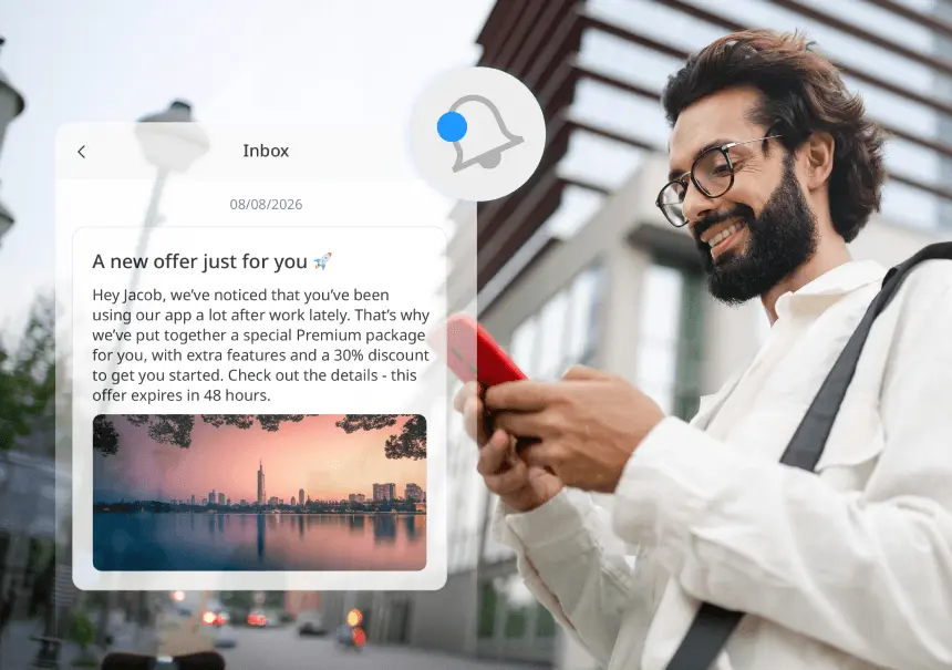 A man using a smartphone with a visible preview of the InBox notification interface in iPresso - a personalized message featuring a bell icon, promotional content, and graphics.