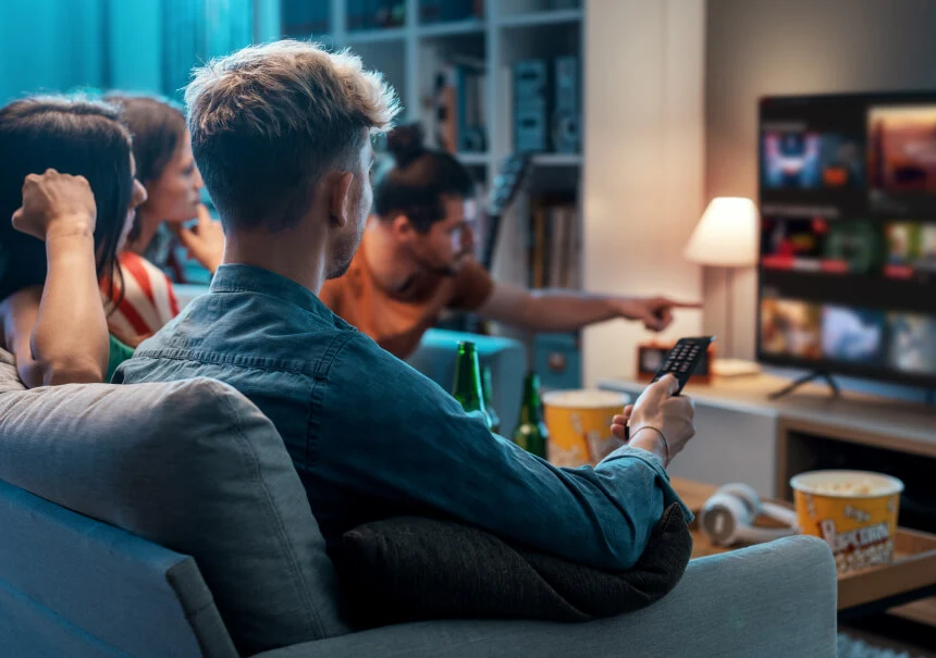 A group of friends watching a movie on a VOD platform, selecting personalized content recommendations on a Smart TV screen using a remote.